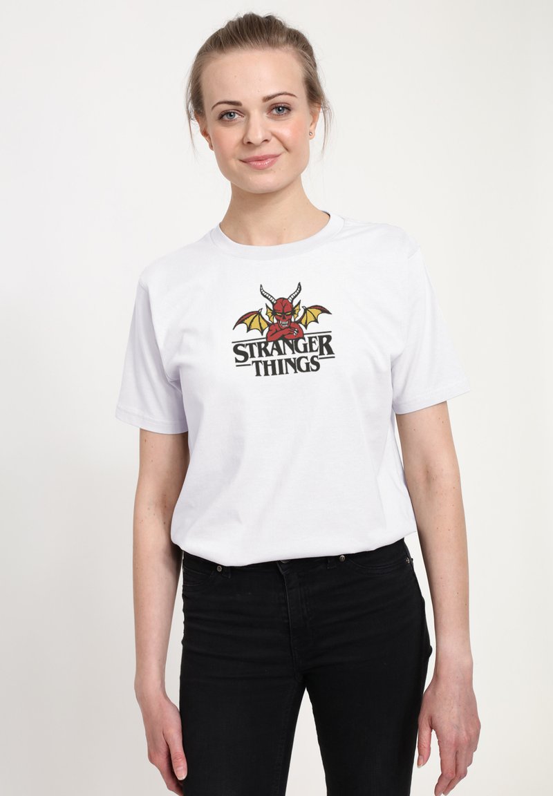 Hvid bomuld T-shirt med en farverig "Stranger Things" grafik med en rød karakter, sort tekst og gule accenter. Casual pasform.