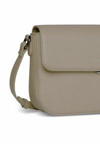 Borsa a tracolla in pelle beige con chiusura a pattina, bordi curvi e tracolla regolabile. Dettaglio di cucitura sottile lungo i bordi.