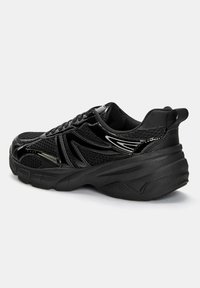 Black athletic shoe featuring a mesh upper, padded collar, and textured rubber sole. Design includes sleek lines and glossy accents.