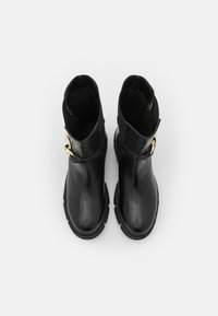 Bottines en cuir noir avec une finition lisse, présentant un accent de boucle dorée, un bout arrondi et une semelle texturée pour une meilleure adhérence.
