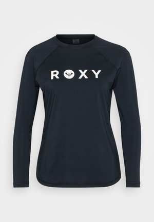 Chemise navy à manches longues avec "ROXY" en grosses lettres blanches sur le devant, fabriquée en tissu doux et lisse, avec des manches raglan et un ourlet arrondi.