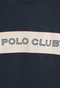Felpa navy con una fascia orizzontale crema che presenta la scritta "POLO CLUB" in testo navy. Collo a girocollo a coste e cuciture di accento rosse. Realizzata in misto cotone.