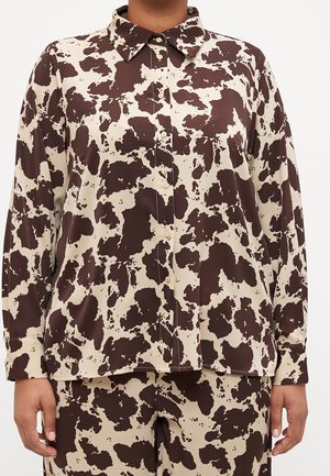 Blusa marrone e crema con un motivo a stampa di mucca, maniche lunghe, chiusura con bottoni davanti e un design del colletto classico.