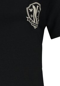 Camiseta de algodón negra con un logo en forma de escudo blanco que presenta un águila, la letra "N" y la frase "UNITAS EST FORTIS". Mangas cortas y cuello redondo.