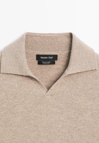 Beige cashmere sweater with a ribbed collar and a V-neck opening, labeled "Massimo Dutti," made in China.