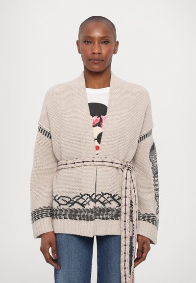 Cardigan tricoté en beige clair avec des motifs géométriques noirs, ouvert à l'avant, avec des manches larges et une ceinture assortie. Fabriqué en fil doux et texturé.
