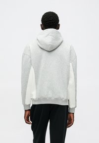 Szara bluza z kapturem o miękkiej fakturze, z białymi bocznymi panelami i ściągaczami przy mankietach. Casualowy design z luźnym krojem.