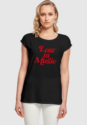 Black short-sleeve t-shirt with a round neckline featuring red text "Lost in Music" in a bold, playful font. Smooth fabric texture.