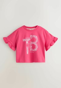 Vaaleanpunainen lyhyt puuvillainen t-paita, jossa on röyhelöity lyhyt hiha ja kukkakuvioitu "TB"-grafiikka, jonka alla sana "BAKER".