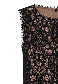 Černá krajková blůza s květinovým vzorem, průhledným designem a nude podšívkou. Vyznačuje se okrajem s malými pom-pomy podél hran.