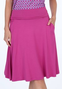 Magenta Rock mit einem dehnbaren Bund. Es verfügt über ein fließendes Design, ist knielang und hat Seitentaschen, hergestellt aus weichem, leichtem Stoff.