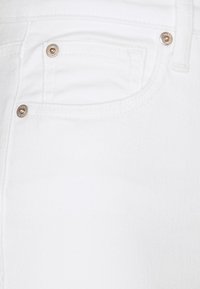 Jeans de mezclilla blanca con un bolsillo frontal con acentos de botones plateados, textura suave y un diseño estructurado.