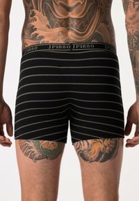 Boxer shorts a righe nere con una cintura beige etichettata "JP1880." La texture appare liscia; il design presenta righe alternate.