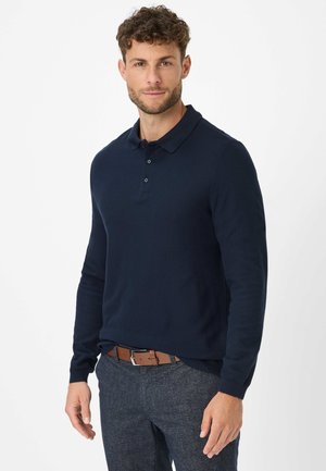 Navyblaues langärmliges Polohemd mit Kragen und Knopfleiste mit drei Knöpfen, aus glattem Stoff gefertigt, kombiniert mit strukturierten grauen Hosen und einem braunen Gürtel.