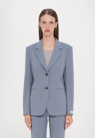 Lichtblauw op maat gemaakte blazer van gestructureerde stof, met twee zwarte knopen, rechte revers en zijzakken. Slanke pasvorm.