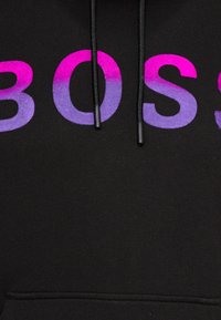 Černá mikina s kapucí s přechodem nápisu "BOSS" v růžové a fialové barvě. Obsahuje černé šňůrky pro nastavitelný střih. Měkká, texturovaná látka.