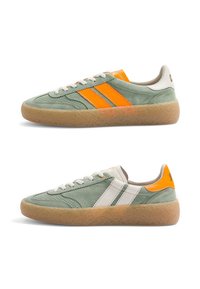 Paire de baskets basses en daim, vertes avec semelles en gomme, avec des bandes orange et blanches et des accents orange au talon.