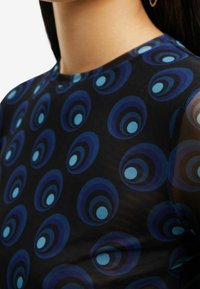 Top nero a maniche corte con un motivo circolare in diverse tonalità di blu, realizzato in un tessuto testurizzato e con scollatura rotonda.