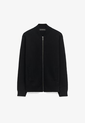 Zwarte bomberjack met rits van gestructureerde stof, met zijzakken, geribde manchetten en een platte kraag. Subtiele logodetail op de zoom.