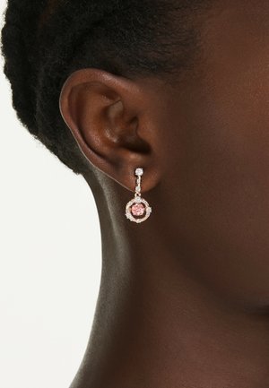 Roséfärgade örhängen med cirkulär design, med en central rosa sten omgiven av klara kristaller och en hängande droppaccent.
