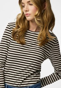 Top a maniche lunghe a righe marroni e crema, con scollo rotondo e vestibilità aderente, abbinato a una fascia in denim in vita.