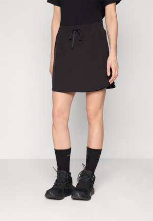 Sort atletisk nederdel med elastisk talje og snor. Parret med sorte sneakers og knælange sorte sokker for et sporty look.