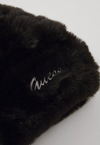 Black faux fur clutch featuring a smooth texture and embroidered "Guess" logo in silver, showcasing a rounded shape.