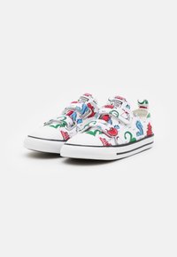 Vita canvas sneakers med färgglada cartoon-mönster i röd, grön och blå. Svart gummisula med vita detaljer och kardborreband.