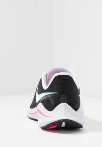 Scarpa sportiva nera con accenti bianchi e dettagli rosa. Presenta una parte superiore in rete testurizzata, colletto imbottito e suola in gomma per una migliore aderenza.