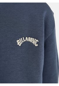 Felpa blu navy con texture a coste, con il testo bianco ricamato "BILLABONG" che si estende arcuato sul petto. Collo a giro, design casual.