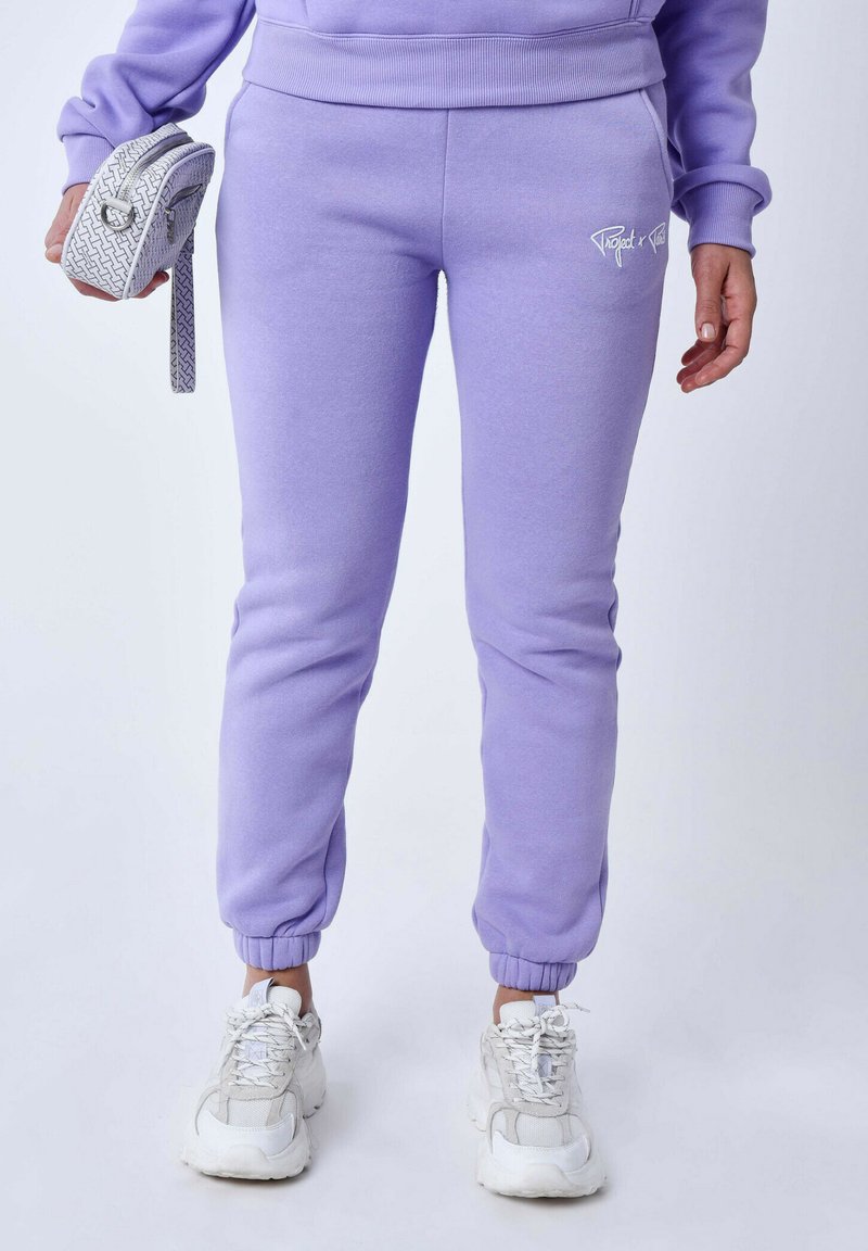 Lila joggingbroeken met elastische boorden en zijvakjes. De stof is lichtgewicht en soepel, gecombineerd met witte chunky sneakers.