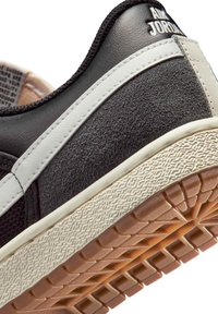 Αθλητικό παπούτσι Air Jordan ασπρόμαυρο που δείχνει υφασμένη σόλα, δερμάτινο επάνω μέρος και λογότυπο στην ταμπέλα της φτέρνας και την επένδυση του γιακά.