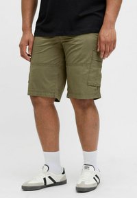 Olive green cargo shorts featuring a straight cut, multiple pockets, and a durable cotton fabric, paired with white socks and sneakers.