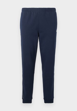 Pantalones jogger con cintura elástica azul marino, tobillos con puños y un sutil detalle de raya lateral.