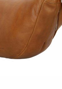 Borsa a spalla in pelle color tan con una texture liscia, forma semi-strutturata, cuciture visibili e un logo in rilievo sottile sul lato.