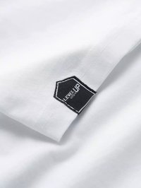 Weißes Baumwoll-T-Shirt mit einem schwarzen, hexagonalen Etikett, auf dem "LEVEL UP" in Weiß gestickt ist. Glatte Textur und schlichte Gestaltung.