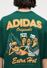 Πράσινο πουκάμισο Adidas Originals με καρτούν καυτερές πιπεριές που φορούν γυαλιά ηλίου και αθλητικά παπούτσια, περιτριγυρισμένες από φλόγες, κρατώντας πινακίδες με τη φράση "I heart".