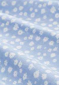 Jasnoniebieska tkanina o teksturowanej powierzchni, z wzorem drobnych białych kwiatów oraz abstrakcyjnych kształtów równomiernie rozmieszczonych.