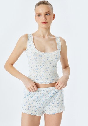 Top en coton léger bleu clair et blanc à motif floral, accompagné de shorts assortis. Présente des bords festonnés et une texture tissée.