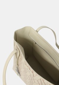 Borsa a spalla beige con un'esterno texturizzato e un sottile motivo geometrico rosa. Dotata di manici doppi e una tasca con zip all'interno.