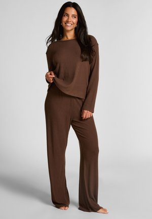 Brown ribbed loungewear set with long sleeves, loose-fitting top, and matching pants. Soft texture and relaxed silhouette.