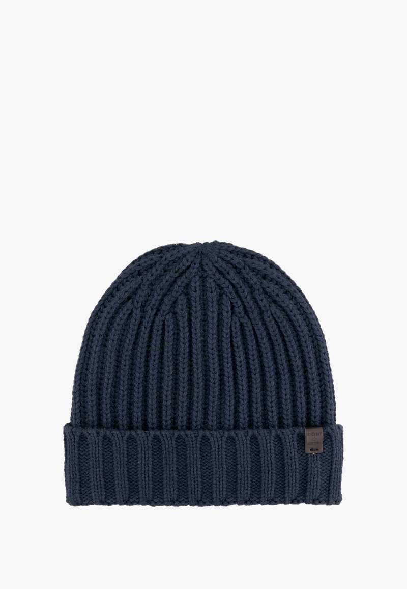 Marine gebreide beanie muts met ribbelstructuur, voorzien van een opgevouwen rand en een klein merklabel aan de zijkant.