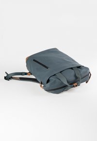 Graublauer Rucksack mit einer glatten, matten Oberfläche, ausgestattet mit einer Frontreißverschluss-Tasche und akzenten aus hellbraunem Leder. Mit verstellbaren Trägern.