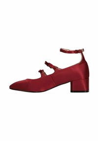 Chaussure en satin rouge avec un talon carré et un bout pointu, ornée de deux nœuds et de brides de cheville ajustables. Texture lisse et design structuré.