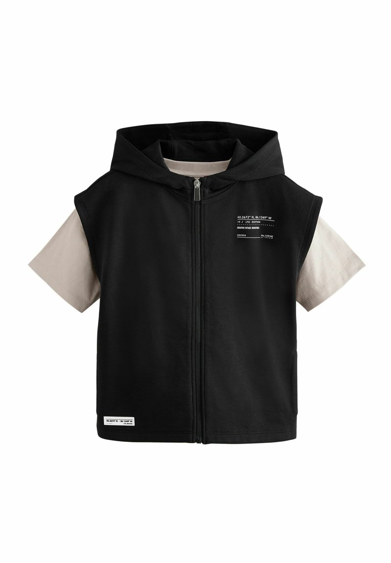 Sort ærmeløs hoodie med frontlynlås. Inkluderer et let beige kortærmet inderlag. Har trykt tekst og et mærke i bunden.