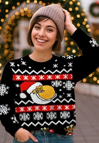 Schwarzer gestrickter Pullover mit einer gelben Figur in einem Weihnachtsmann-Hut, roten und weißen Schneeflocken sowie einem festlichen Muster. Getragen mit einer beigen Mütze.