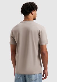 Beige T-shirt met korte mouwen en een ronde hals, gemaakt van zachte stof, met een gladde structuur en een ontspannen pasvorm. Zichtbare stikseldetails bij de zoom.