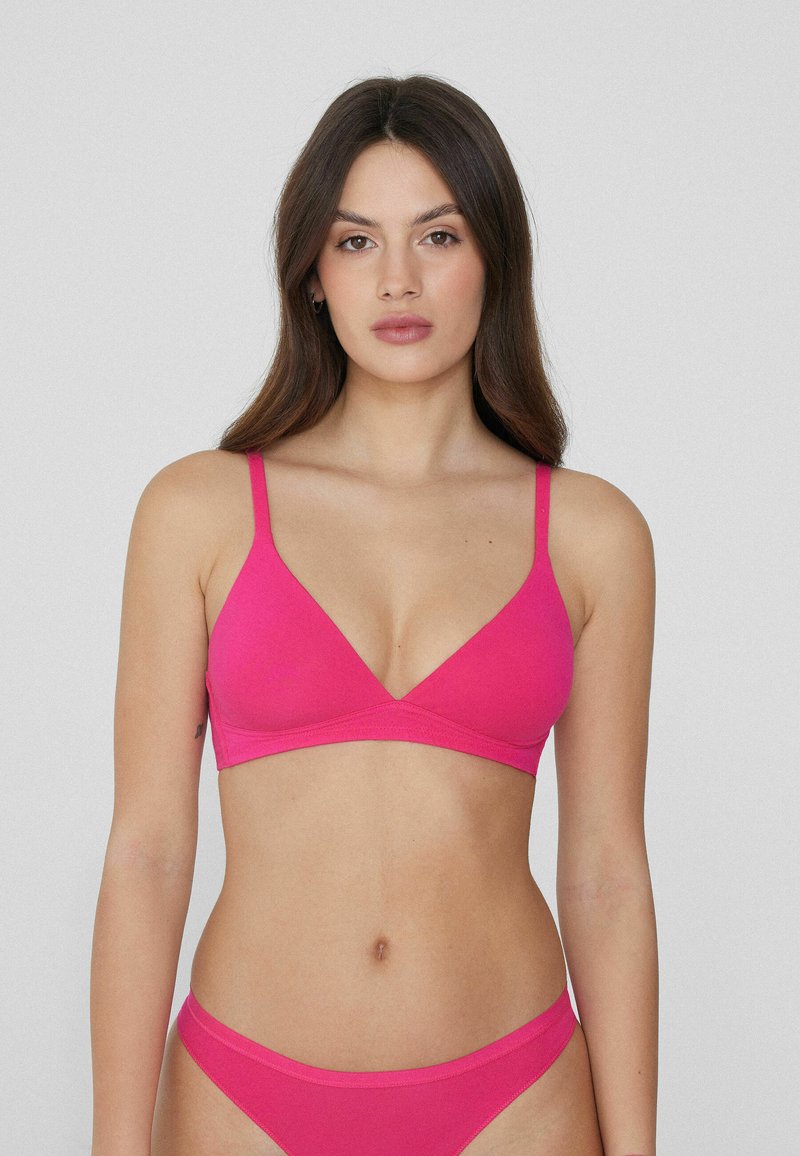 Sujetador triangular rosa con tirantes finos, confeccionado en una tela suave. Presenta un diseño simple y un borde sutil a lo largo de la banda.