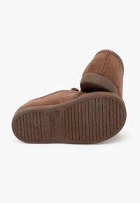 Botine maronii din suede, cu o textură fină, închidere cu fermoar și o talpă din cauciuc flexibilă, cu un model striat. Fabricate în Spania.