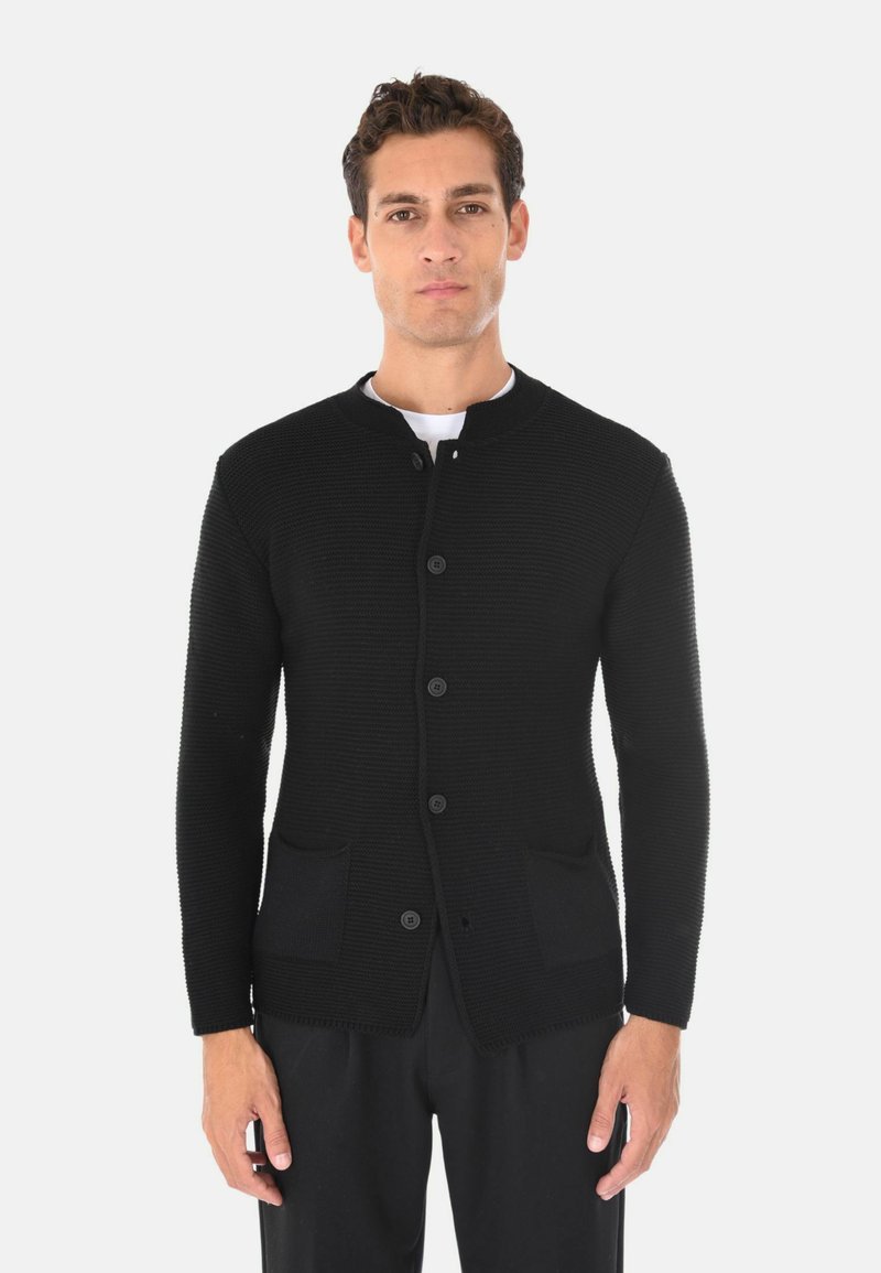 Cardigan nero in maglia con scollo rotondo, bottoni frontali e due tasche anteriori. Il tessuto è testurizzato e aderente.